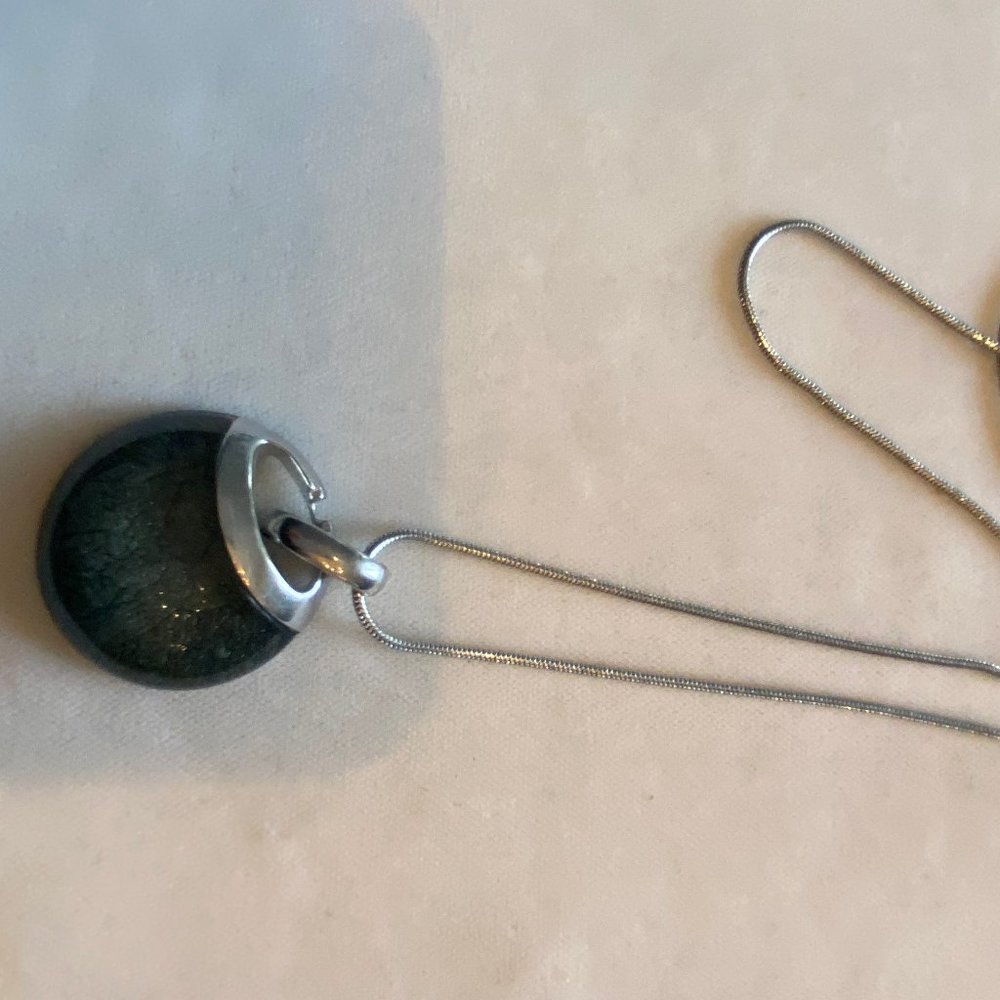 - Grey stone encased in silver pendant;  26" chain